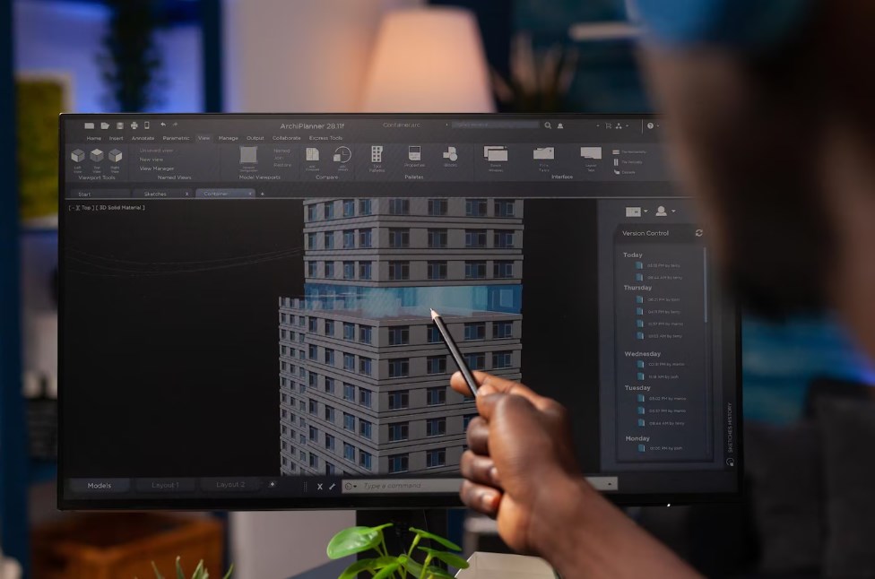 an architect engineer pointing at an architectural building prototype and analyzing